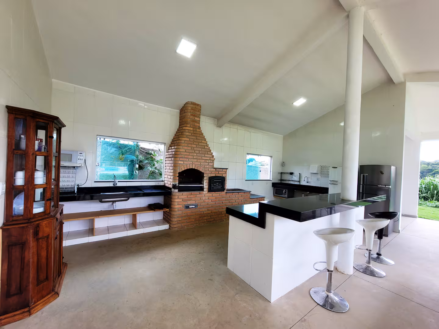 Cozinha gourmet aberta com churrasqueira, bancadas e banquetas